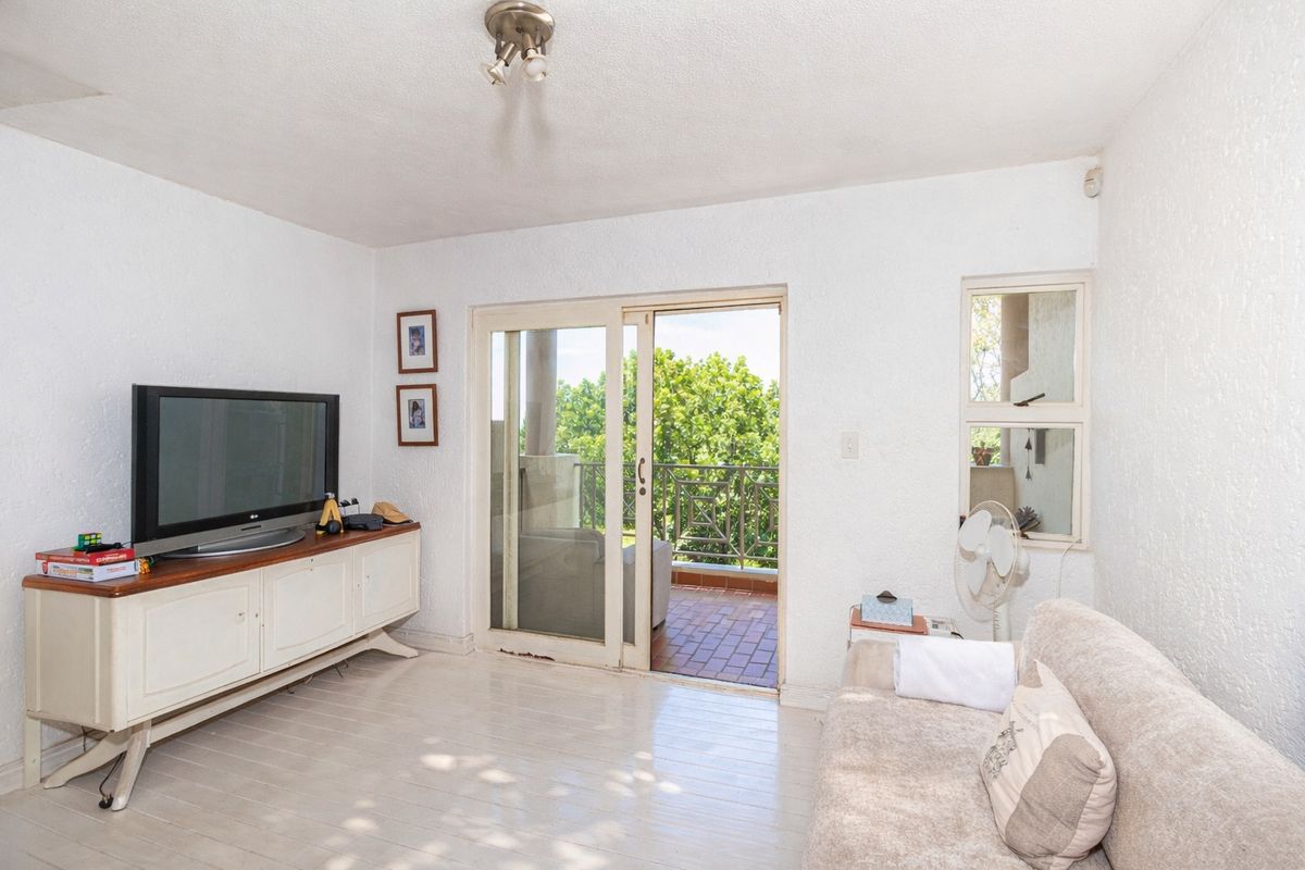 Living room featuring textured walls, a sliding glass door leading to a balcony, and a window providing natural light.