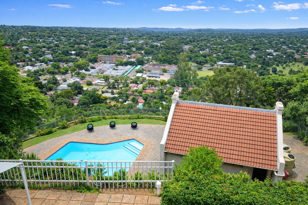 Aerial view of a townhouse property featuring a private swimming pool, paved patio area, and expansive suburban landscape views.
