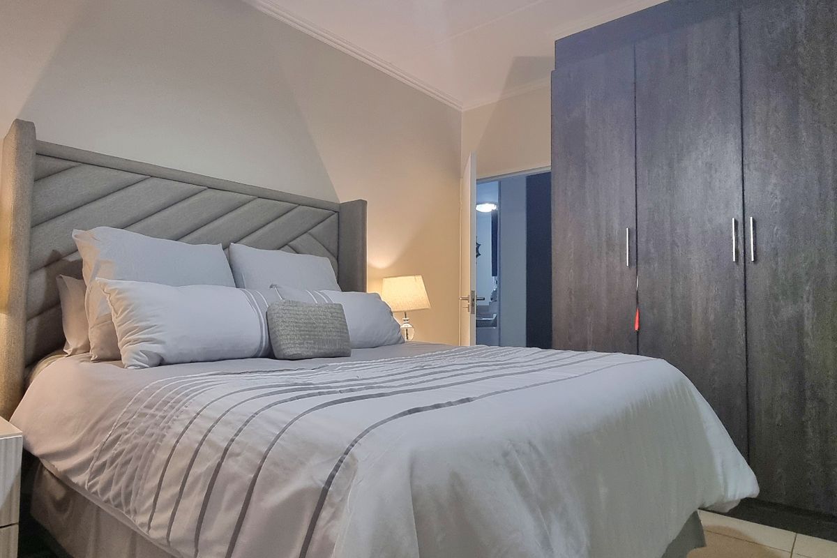 A well-maintained bedroom featuring a large built-in wardrobe with dark wood-grain finish and decorative ceiling coving.