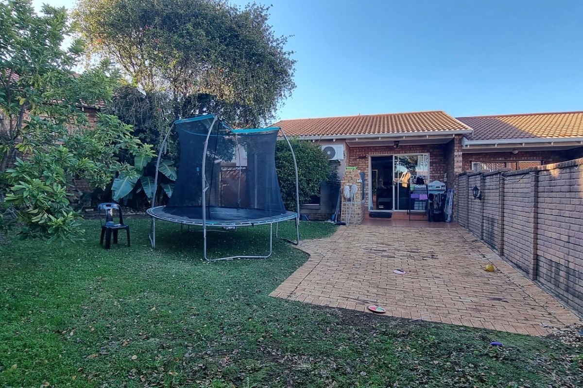 A private rear garden featuring a paved patio area, lawn, and brick boundary walls, providing a functional outdoor space for the townhouse.
