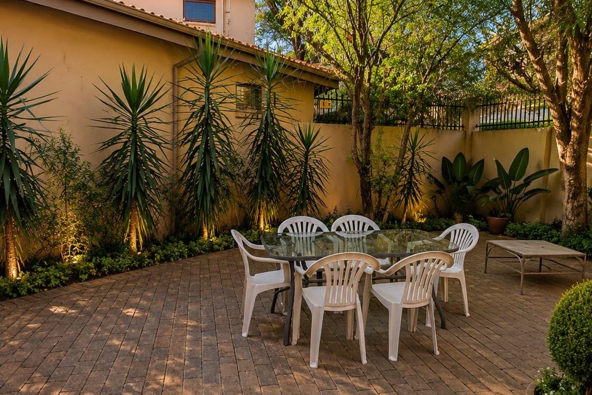 A private rear courtyard featuring paved flooring, established trees, and perimeter walling, providing a tranquil outdoor entertainment space.