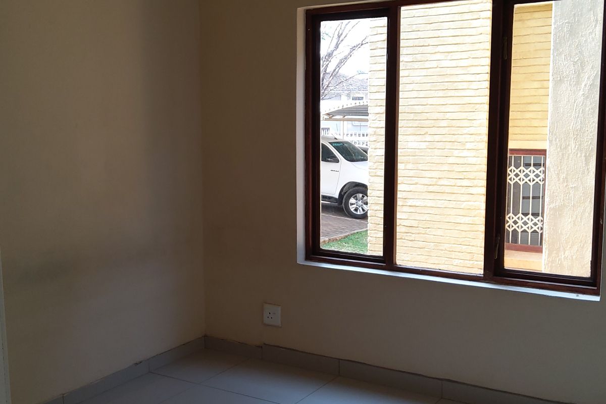 An empty bedroom featuring neutral wall paint, tiled flooring, and a ceiling fan, offering a clean and versatile space.