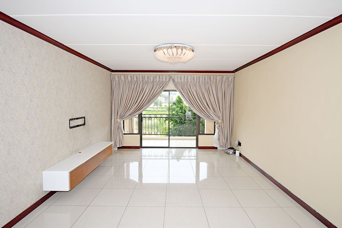 Spacious living room featuring polished tile flooring, a built-in media console, and sliding glass doors leading to a private balcony.