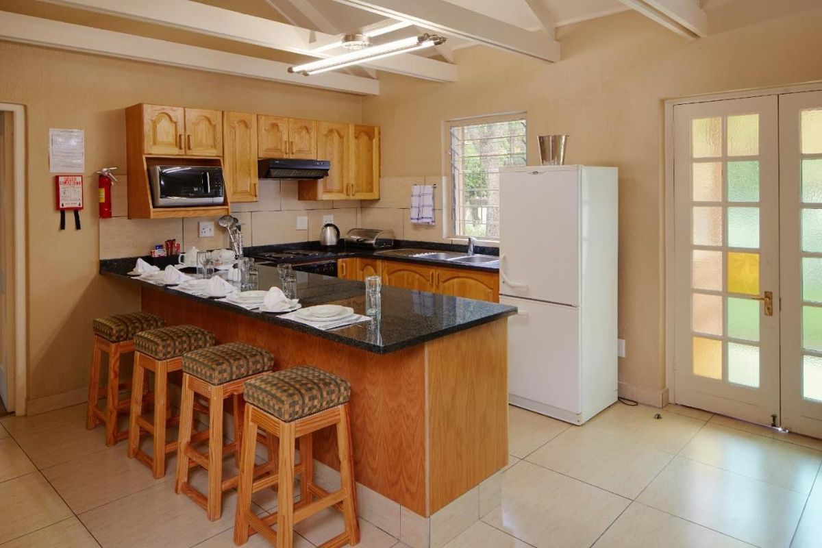 A functional kitchen featuring wooden cabinetry, granite countertops, a breakfast bar, and exposed ceiling beams, with direct access to the exterior via a french door.