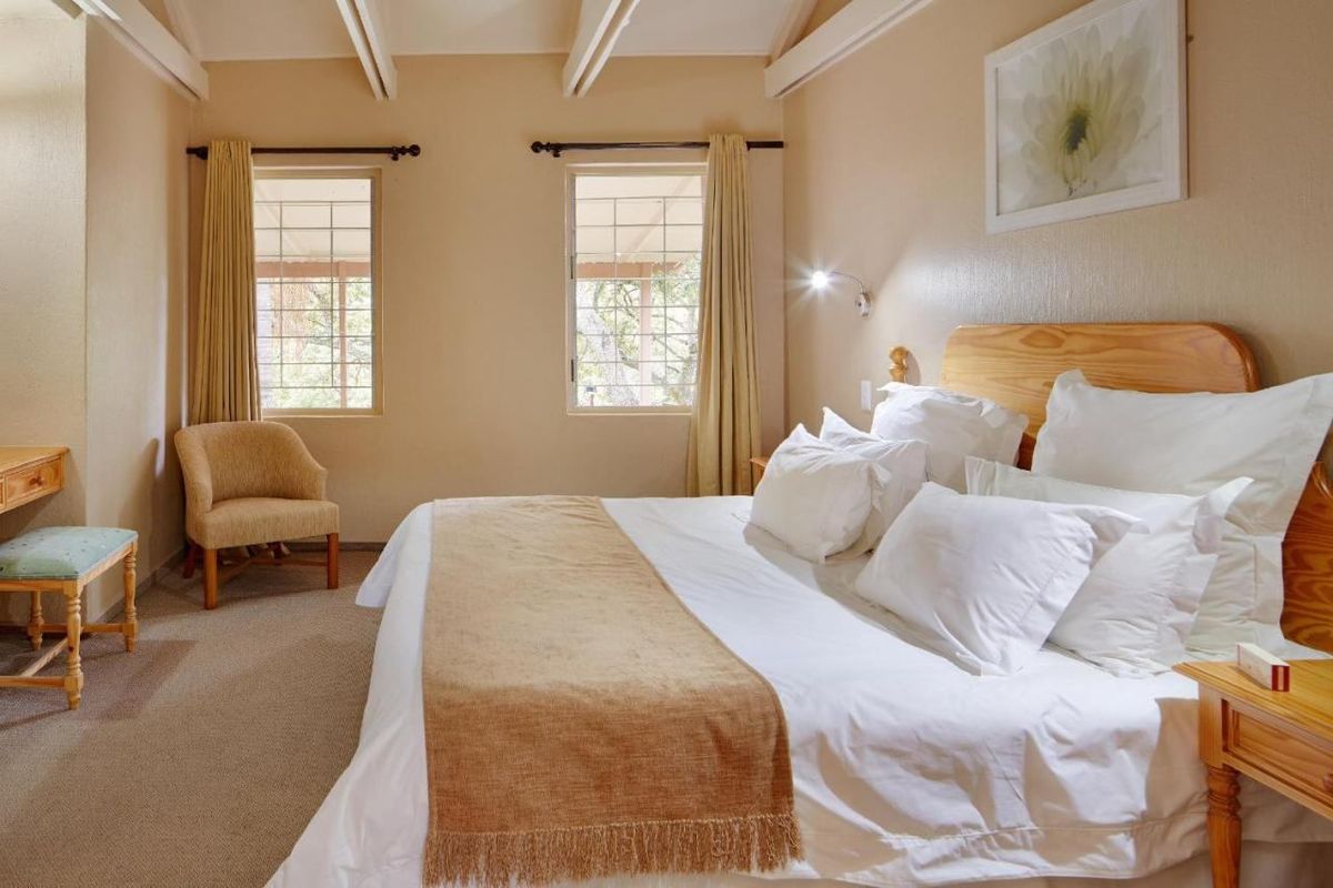 A well-maintained bedroom featuring exposed ceiling beams, neutral wall tones, and dual windows with security bars, providing a comfortable and bright living space.