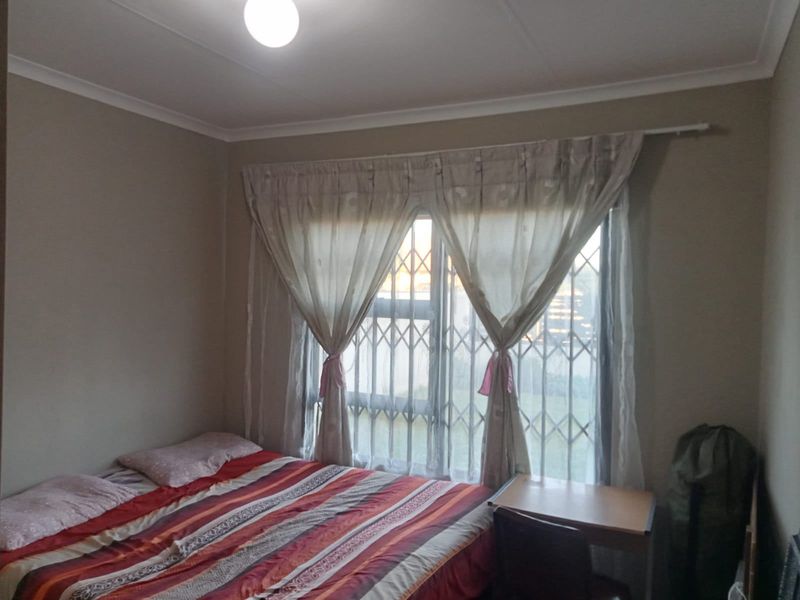 A standard bedroom featuring a window with a fitted security gate and cove cornicing.