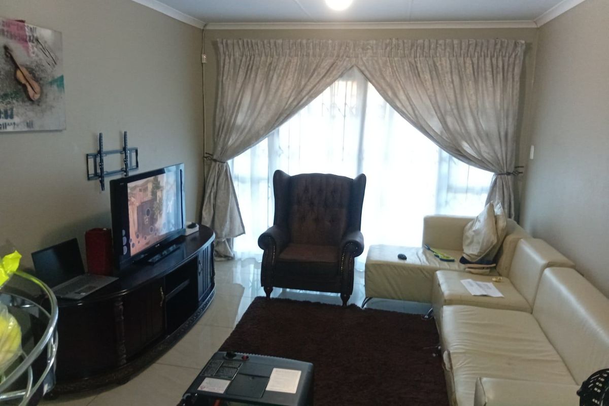 A comfortable living room featuring tiled flooring and a large sliding glass door that provides natural light, creating a functional and inviting space.