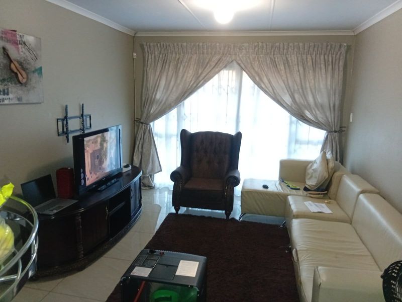 A comfortable living room featuring tiled flooring and a large sliding glass door that provides natural light, creating a functional and inviting space.