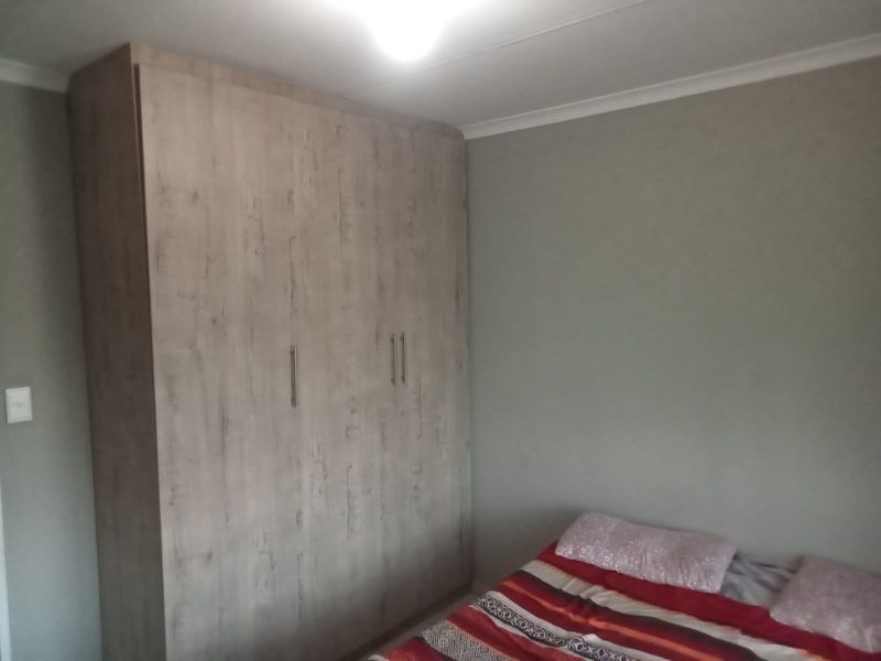 A bedroom featuring a modern wood-grain finish built-in wardrobe and neutral wall tones.