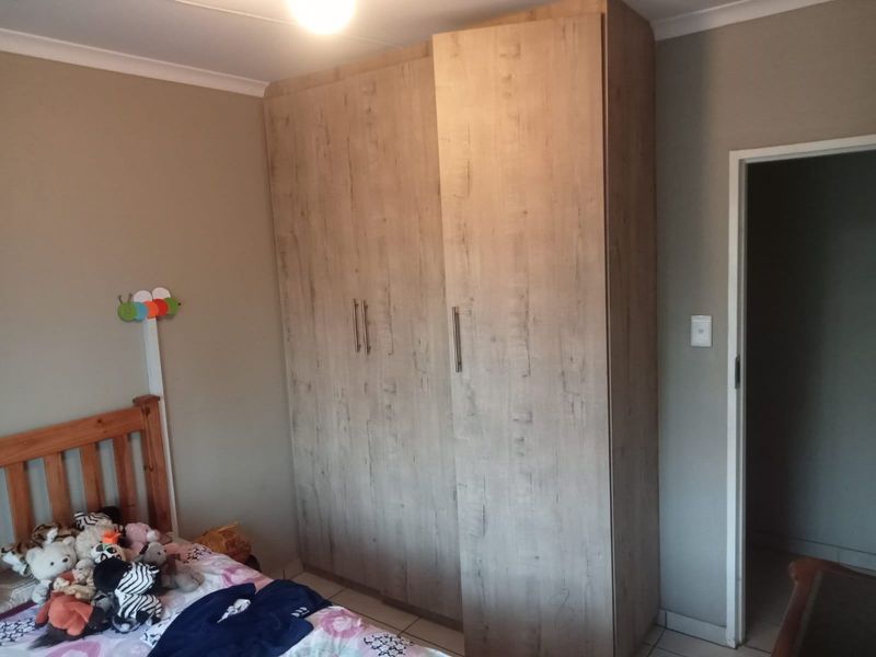 A bedroom featuring a large, modern wood-finish built-in wardrobe and tiled flooring.