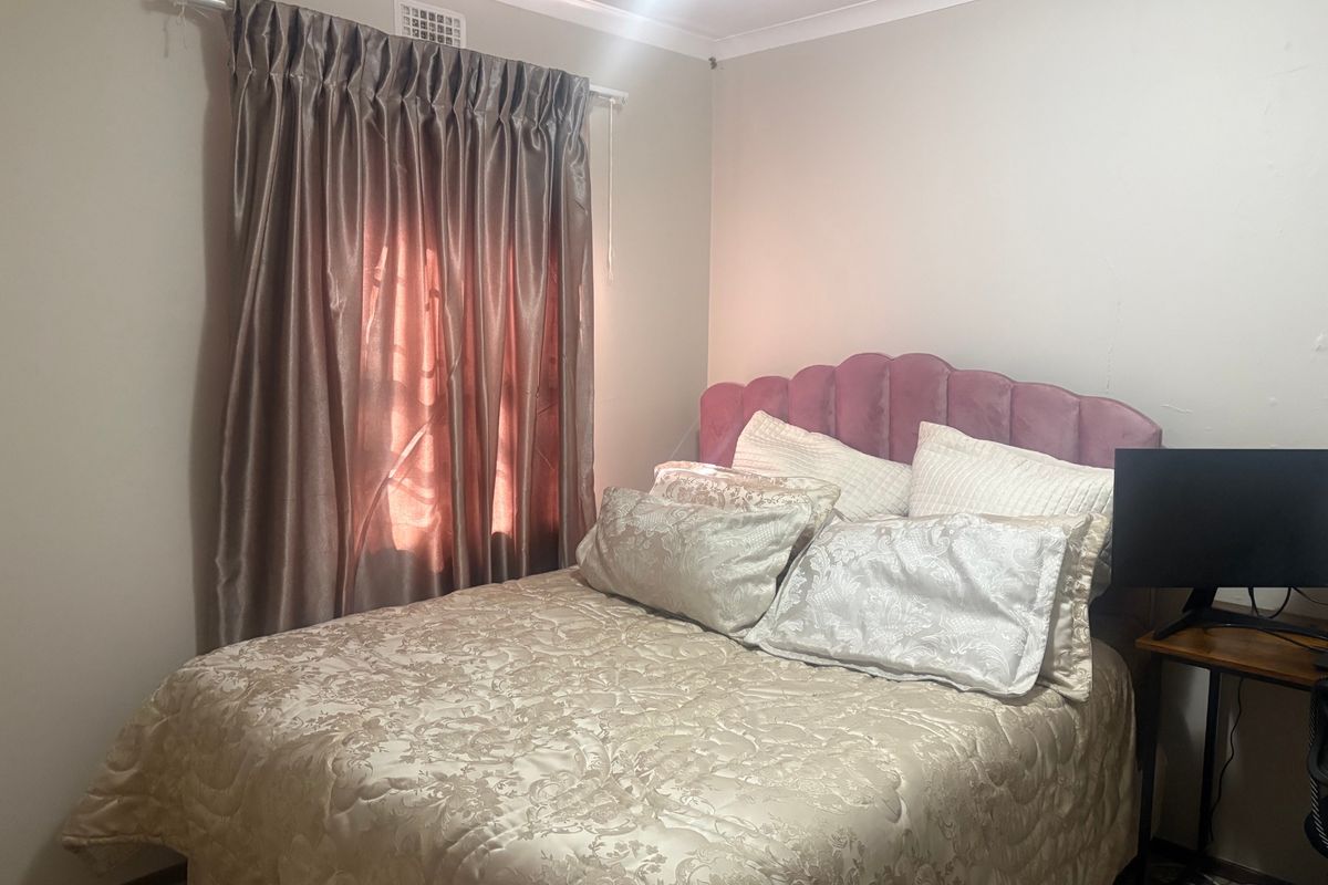 A standard bedroom featuring neutral wall finishes, coving, and a wall-mounted air vent.