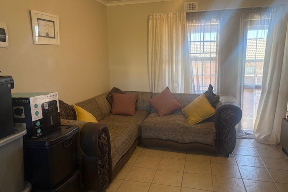A living room featuring tiled flooring and neutral wall finishes, providing a functional space with natural light from the window.