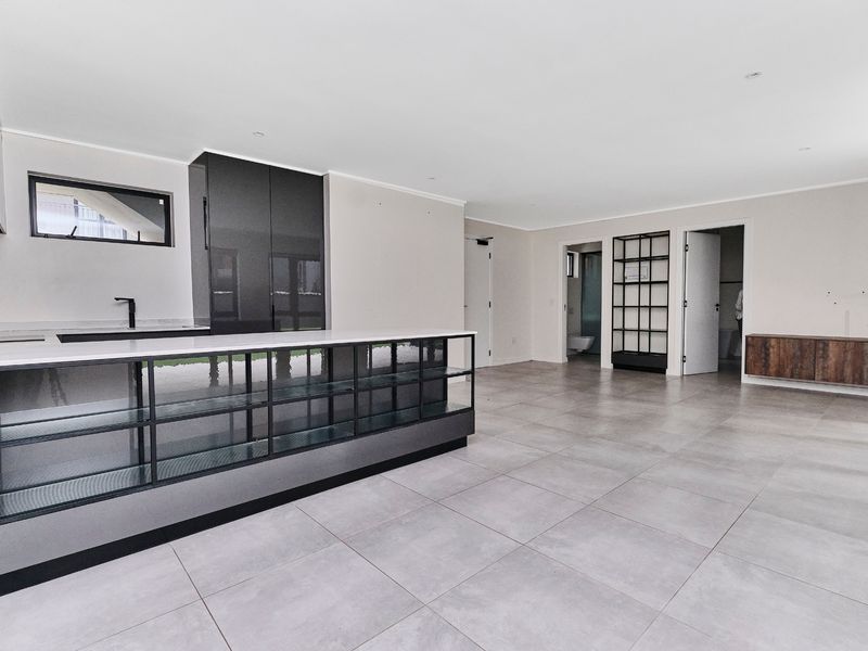 Spacious open-plan living area featuring modern kitchen cabinetry, a central island with stone countertops, and large format floor tiles throughout.