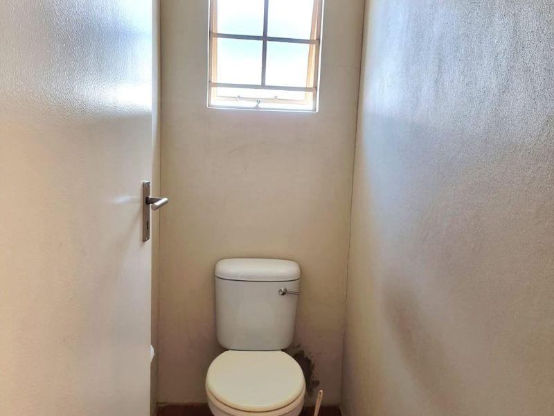A compact, functional guest toilet featuring tiled flooring and a small window for natural light and ventilation.
