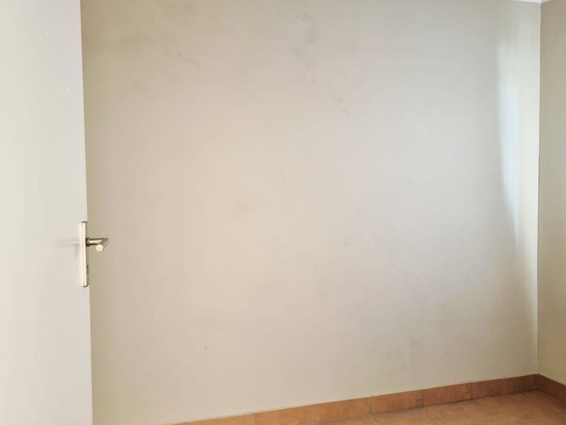 An empty bedroom featuring tiled flooring, coving, and a neutral wall finish, providing a blank canvas for potential interior design updates.