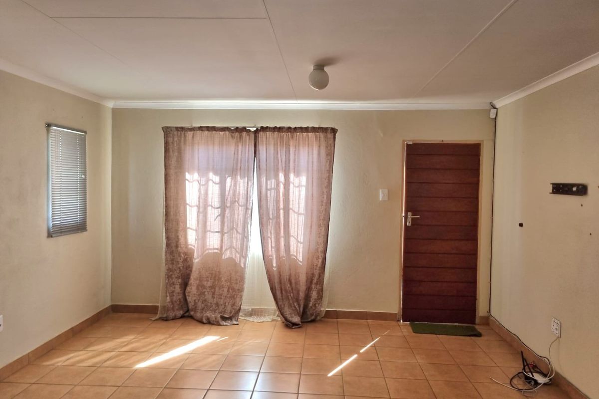 An empty living room featuring tiled flooring, a timber entrance door, and coved ceilings, offering a blank canvas for interior design.