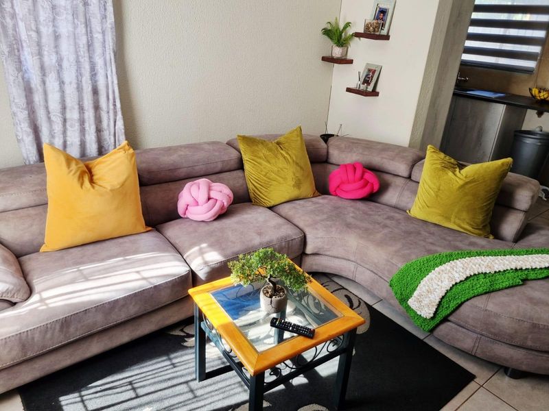 A comfortable living room area featuring tiled flooring and wall-mounted floating shelves, providing a functional and cozy space.
