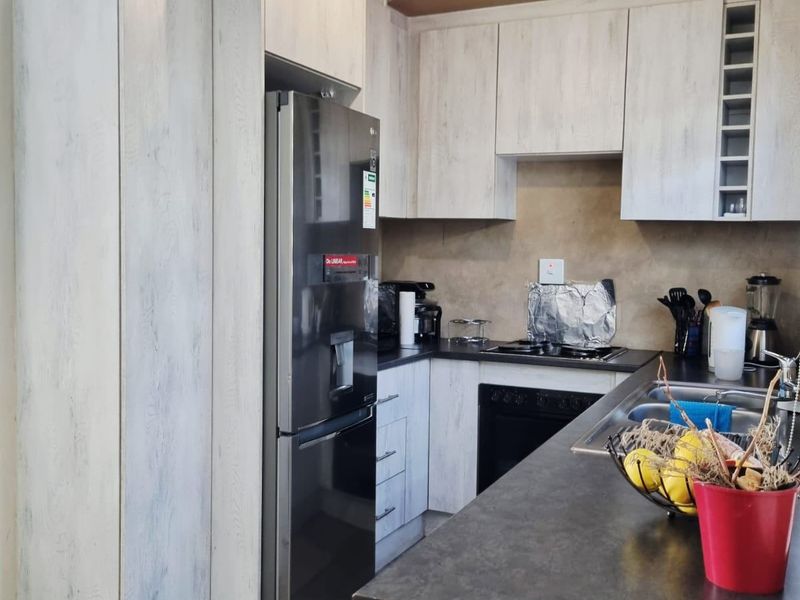 Kitchen featuring light wood-grain cabinetry, dark countertops, and integrated appliances. The space requires ceiling finishing to complete the renovation.