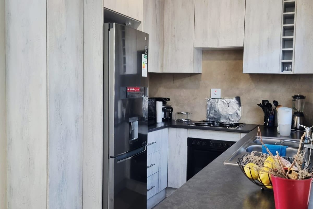 Kitchen featuring light wood-grain cabinetry, dark countertops, and integrated appliances. The space requires ceiling finishing to complete the renovation.