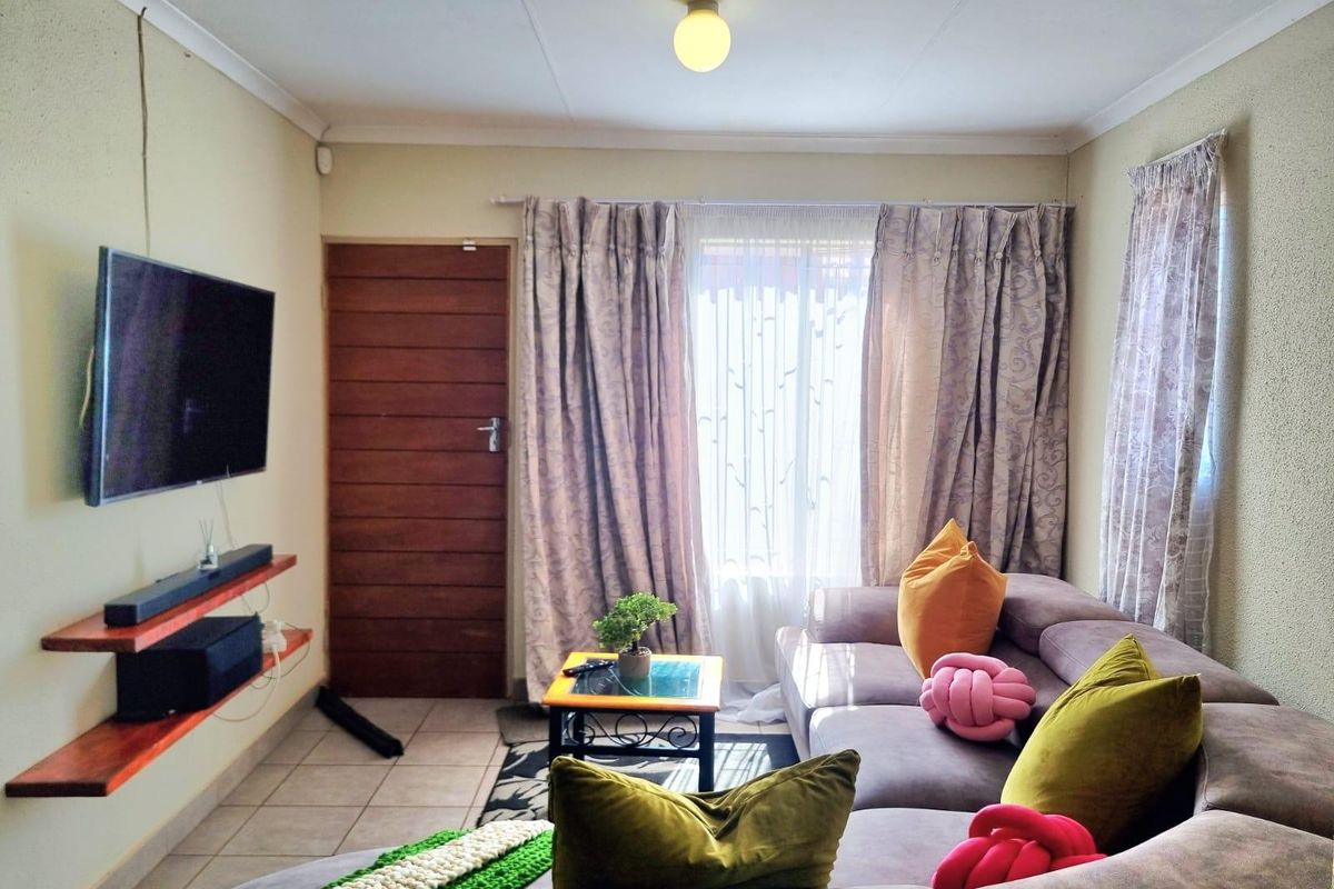 A cozy living room featuring tiled flooring, a timber entrance door, and wall-mounted shelving, providing a functional and comfortable living space.