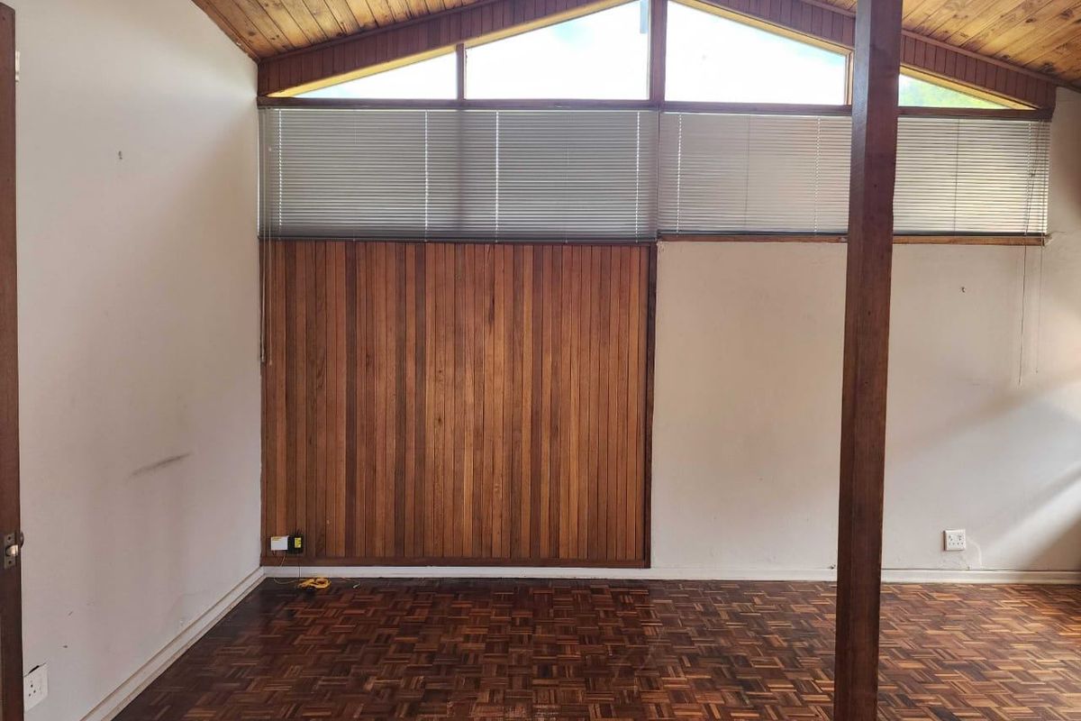 Empty living room featuring parquet flooring, a timber-clad feature wall, and an exposed timber raked ceiling with clerestory windows.
