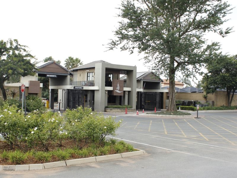A well-maintained commercial security gatehouse and access control point featuring paved driveways and landscaped surroundings.