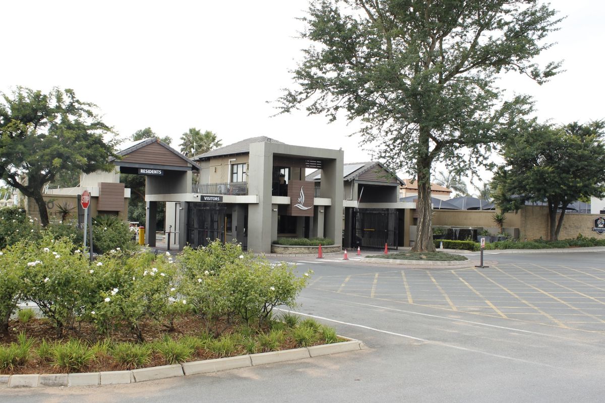 A well-maintained commercial security gatehouse and access control point featuring paved driveways and landscaped surroundings.