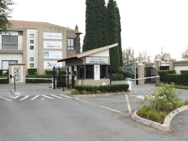 The entrance to Clear Water Office Park featuring a security guard house, boom gate access control, and well-maintained landscaped grounds.