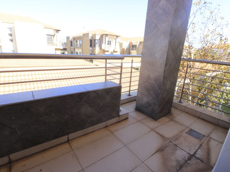 A spacious balcony featuring tiled flooring, a central tiled pillar, and stainless steel balustrades, offering an open outdoor area for relaxation.