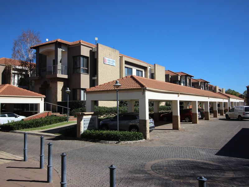 A well-maintained commercial office park featuring covered parking bays, paved driveways, and modern building facades with tiled roofing.