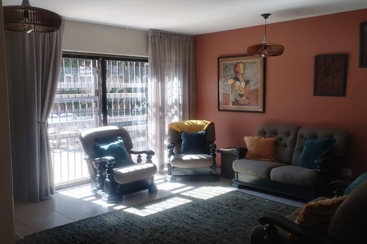 A comfortable living room featuring tiled flooring and a large sliding glass door that provides access to the outdoor area.