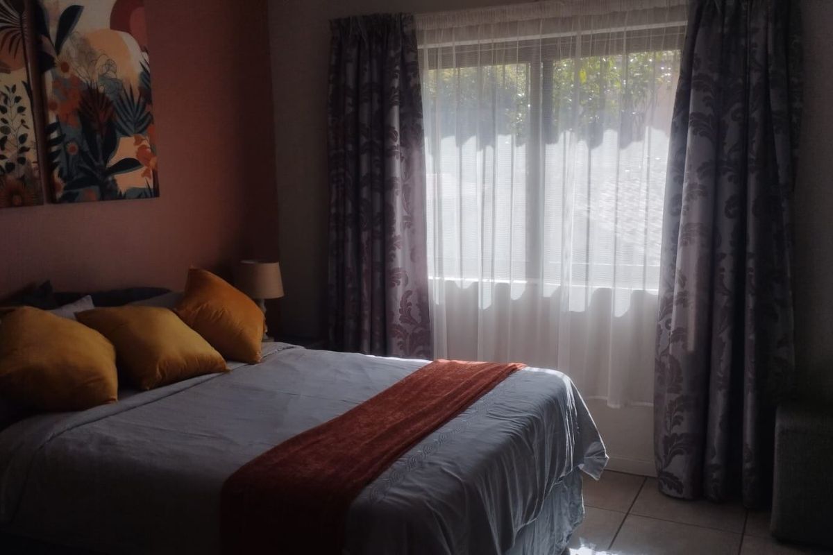 A bedroom featuring tiled flooring and window treatments, providing a functional space with natural light.