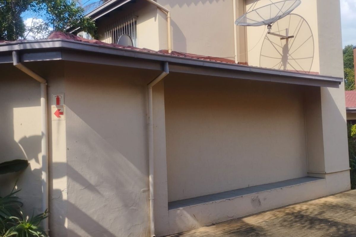 Exterior view of the townhouse rear facade featuring paved ground, guttering, and a satellite dish installation.
