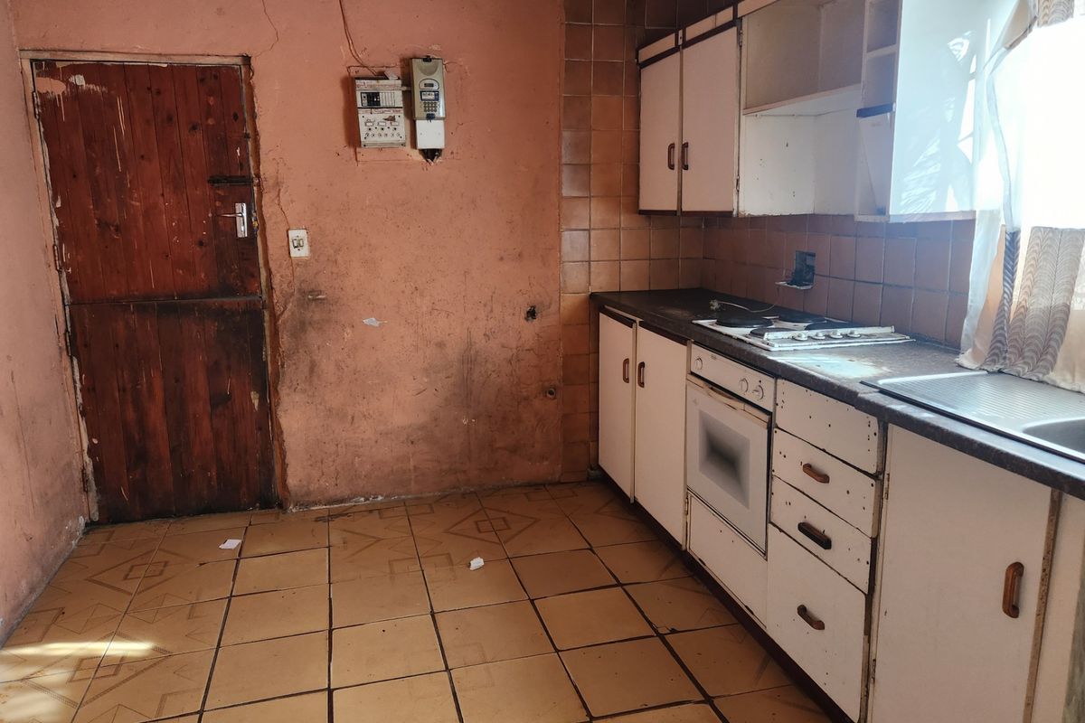 A dated kitchen featuring built-in cabinetry, an electric hob, and oven, requiring significant renovation and cosmetic updates to restore functionality and aesthetic appeal.