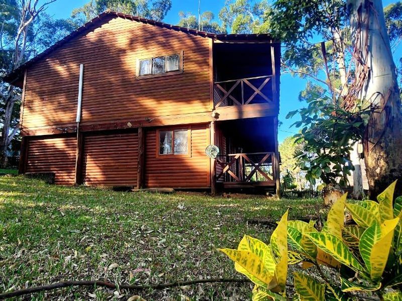A two-story timber-clad townhouse exterior featuring a rear balcony and deck, set within a landscaped garden area.