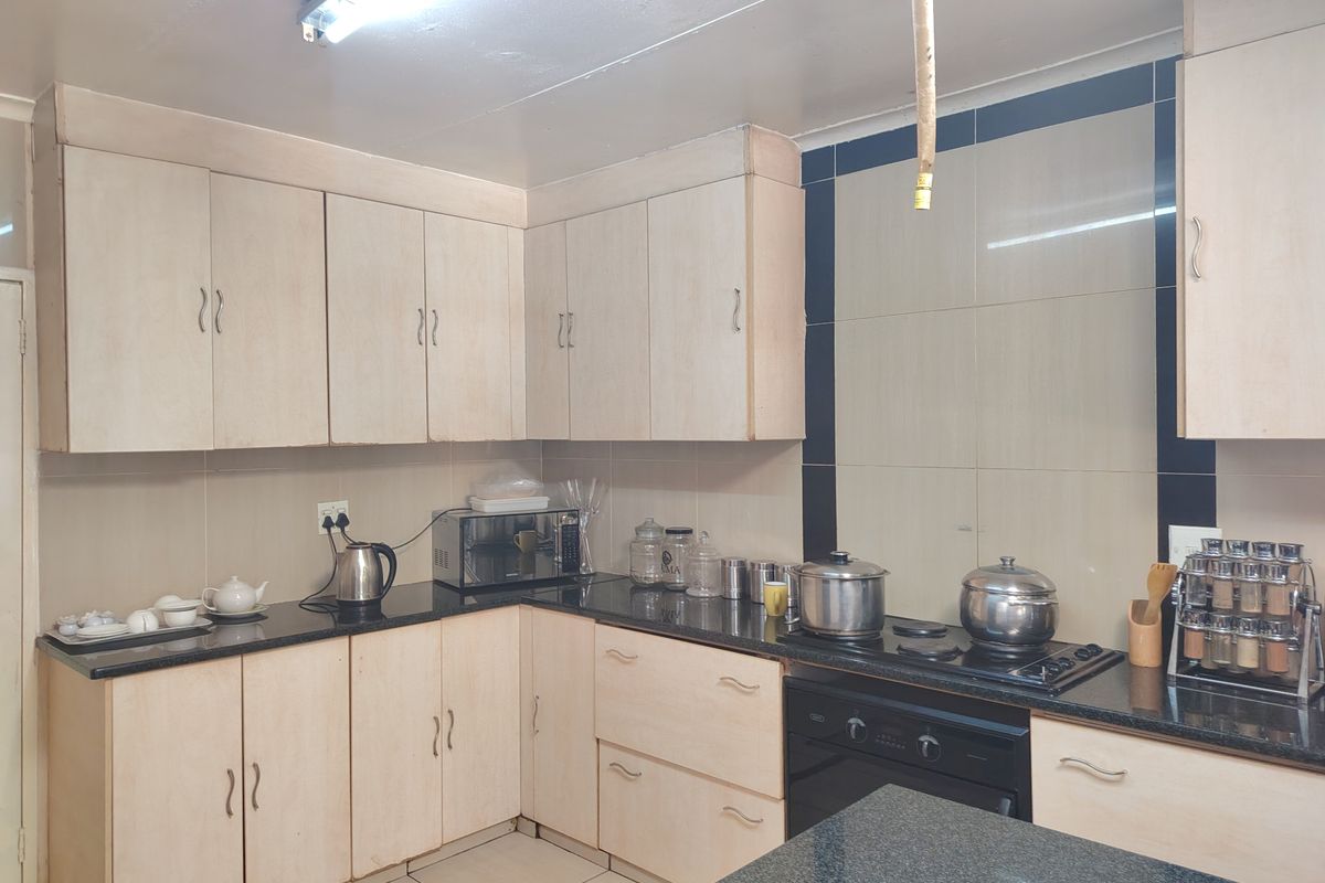 A functional kitchen featuring light-toned built-in cabinetry, dark granite countertops, a built-in oven and hob, and tiled splashbacks.