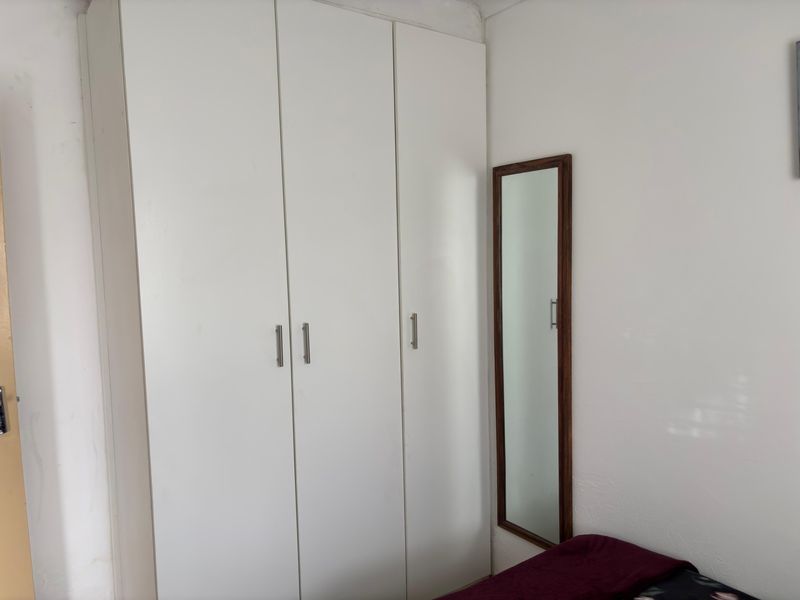 A bedroom featuring a white built-in wardrobe with modern handles, providing ample storage space.