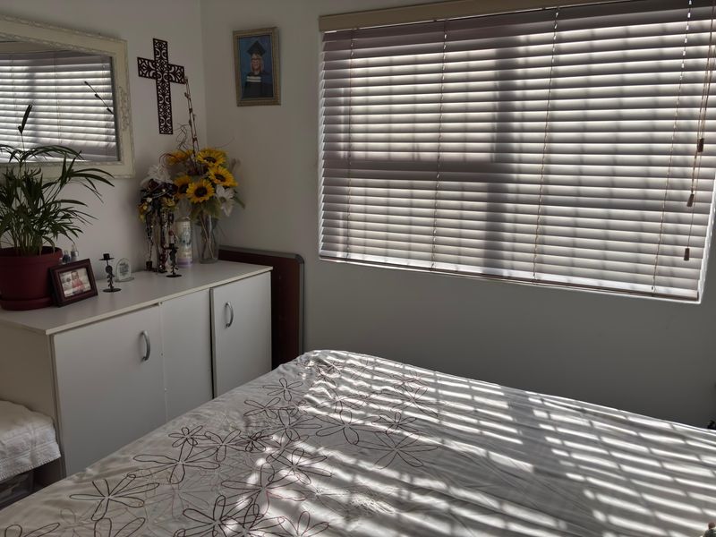 A bedroom featuring neutral walls and fitted venetian blinds, providing natural light control.