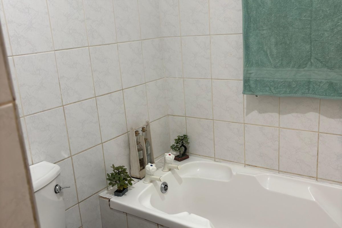 A functional bathroom featuring a built-in bathtub, toilet, and tiled wall finishes, providing a practical space for daily use.