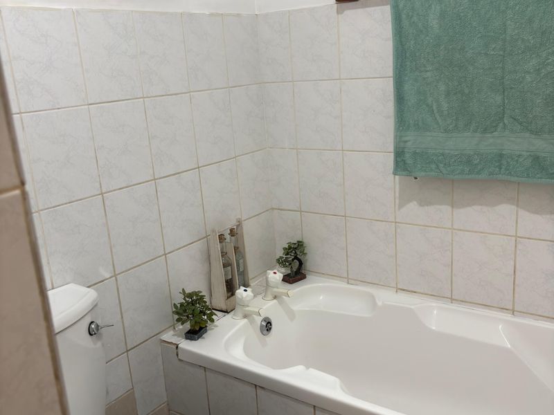 A functional bathroom featuring a built-in bathtub, toilet, and tiled wall finishes, providing a practical space for daily use.
