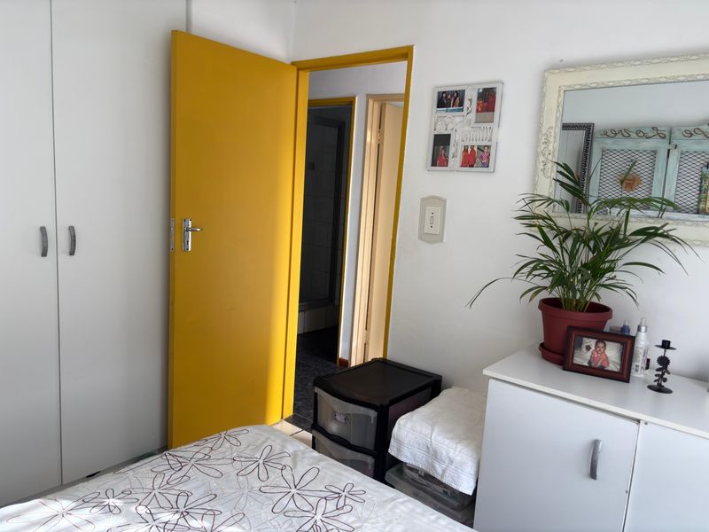 A bedroom featuring a built-in wardrobe and a bright yellow interior door leading to an adjacent room.