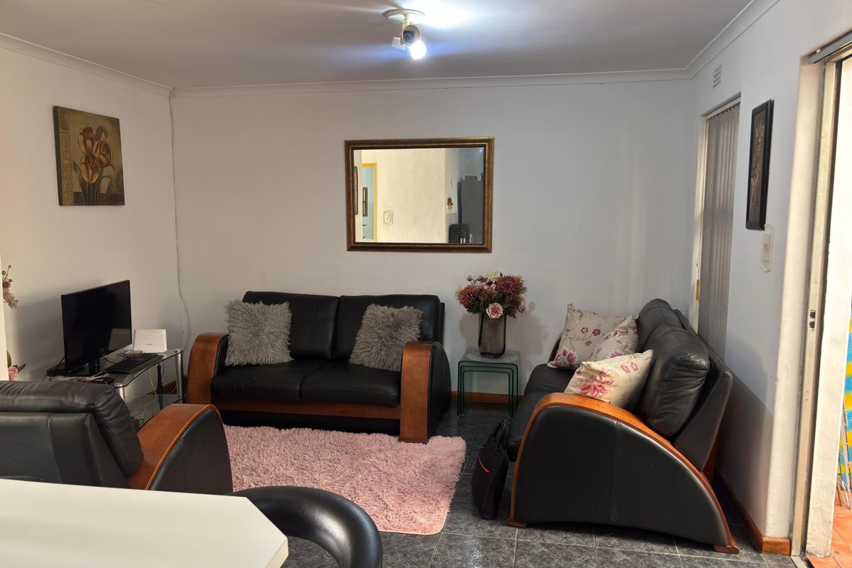 A functional living room featuring tiled flooring, cove cornicing, and a sliding door providing access to the exterior.