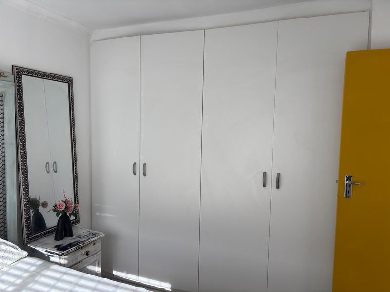 A bedroom featuring a large, white built-in wardrobe with modern handles, providing ample storage space.