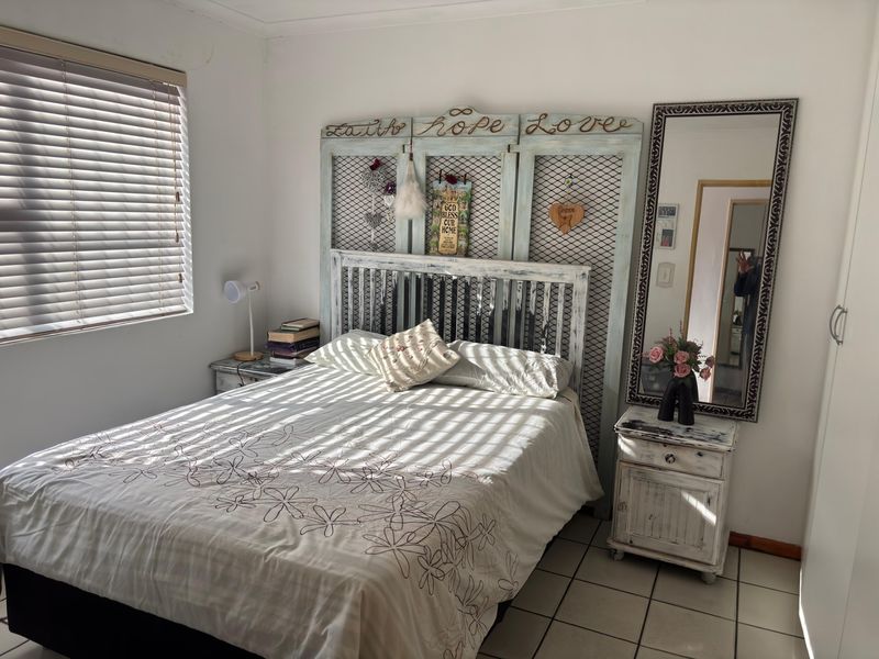 A bedroom featuring tiled flooring, built-in wardrobe storage, and venetian blinds, offering a functional space with neutral wall finishes.