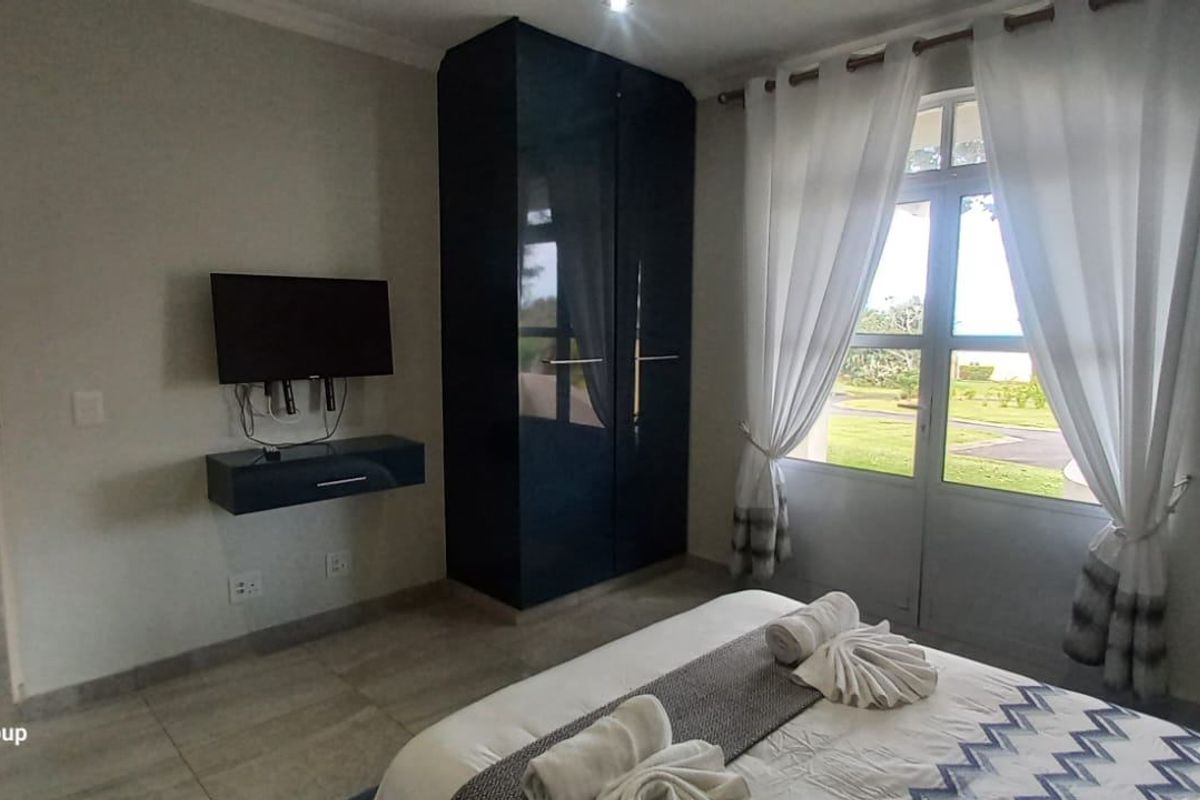 A well-maintained bedroom featuring tiled flooring, a built-in wardrobe, and a glass sliding door providing access to the exterior.