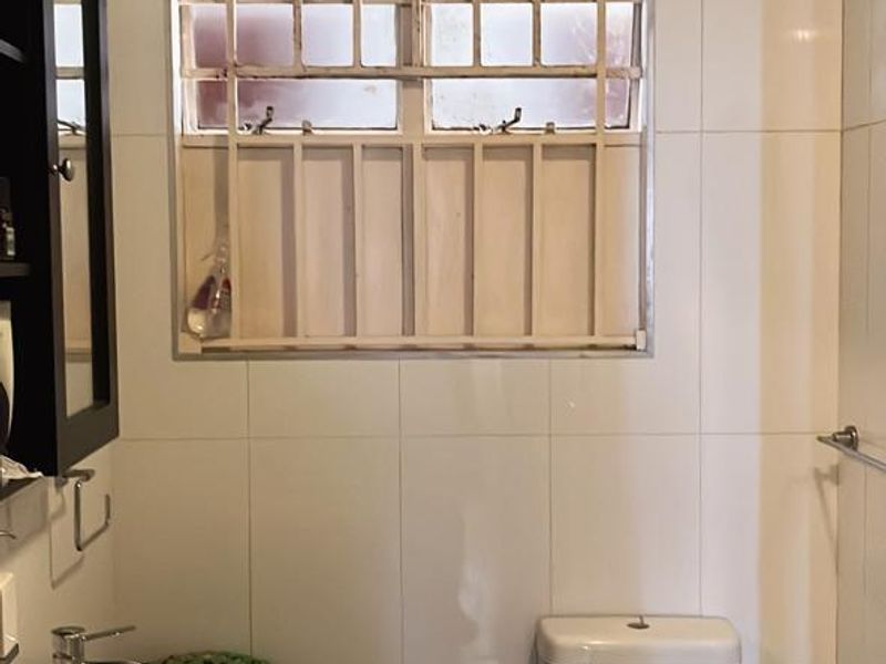 A bathroom featuring a dual vanity setup and a toilet, currently showing significant ceiling water damage and signs of wear requiring maintenance.