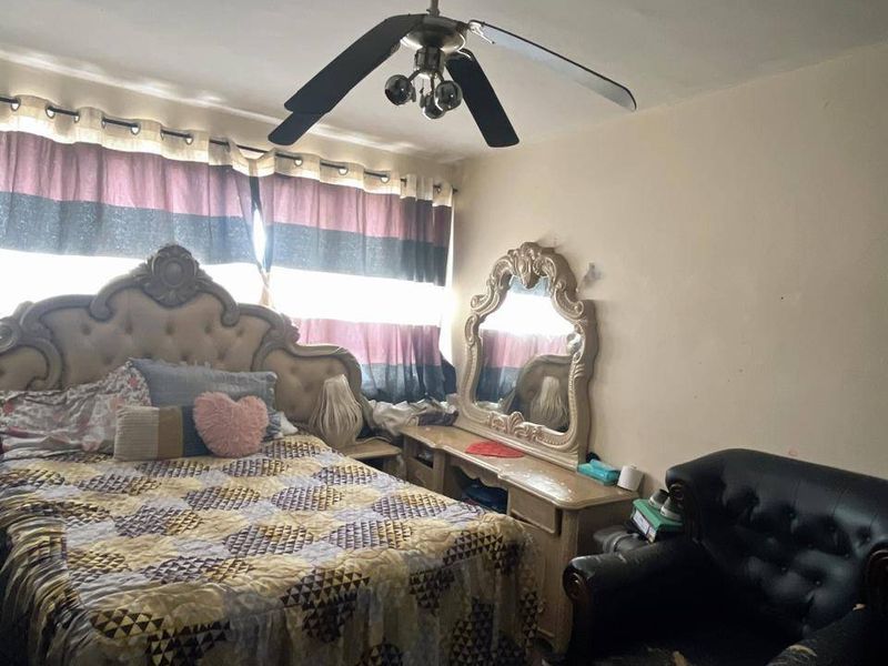 A bedroom featuring a ceiling fan and parquet flooring, requiring cosmetic updates to the wall finishes.