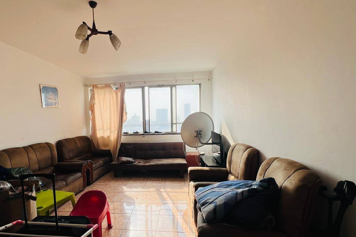 A living room featuring tiled flooring and a large window with natural light, offering a functional space ready for modernization and aesthetic updates.