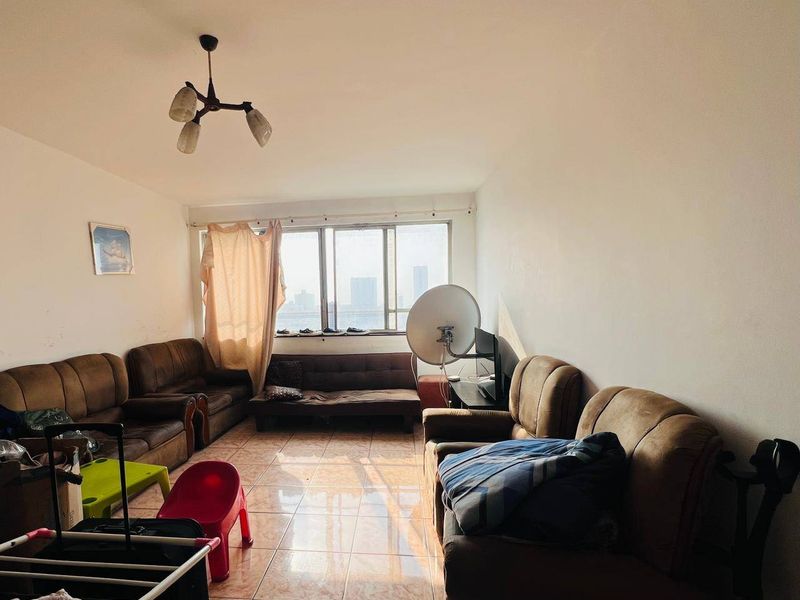 A living room featuring tiled flooring and a large window with natural light, offering a functional space ready for modernization and aesthetic updates.