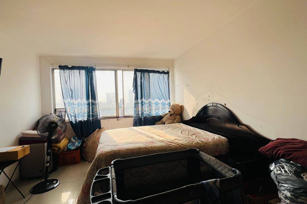 A bedroom featuring tiled flooring and a large sliding window, currently requiring cosmetic updates to the wall finishes.